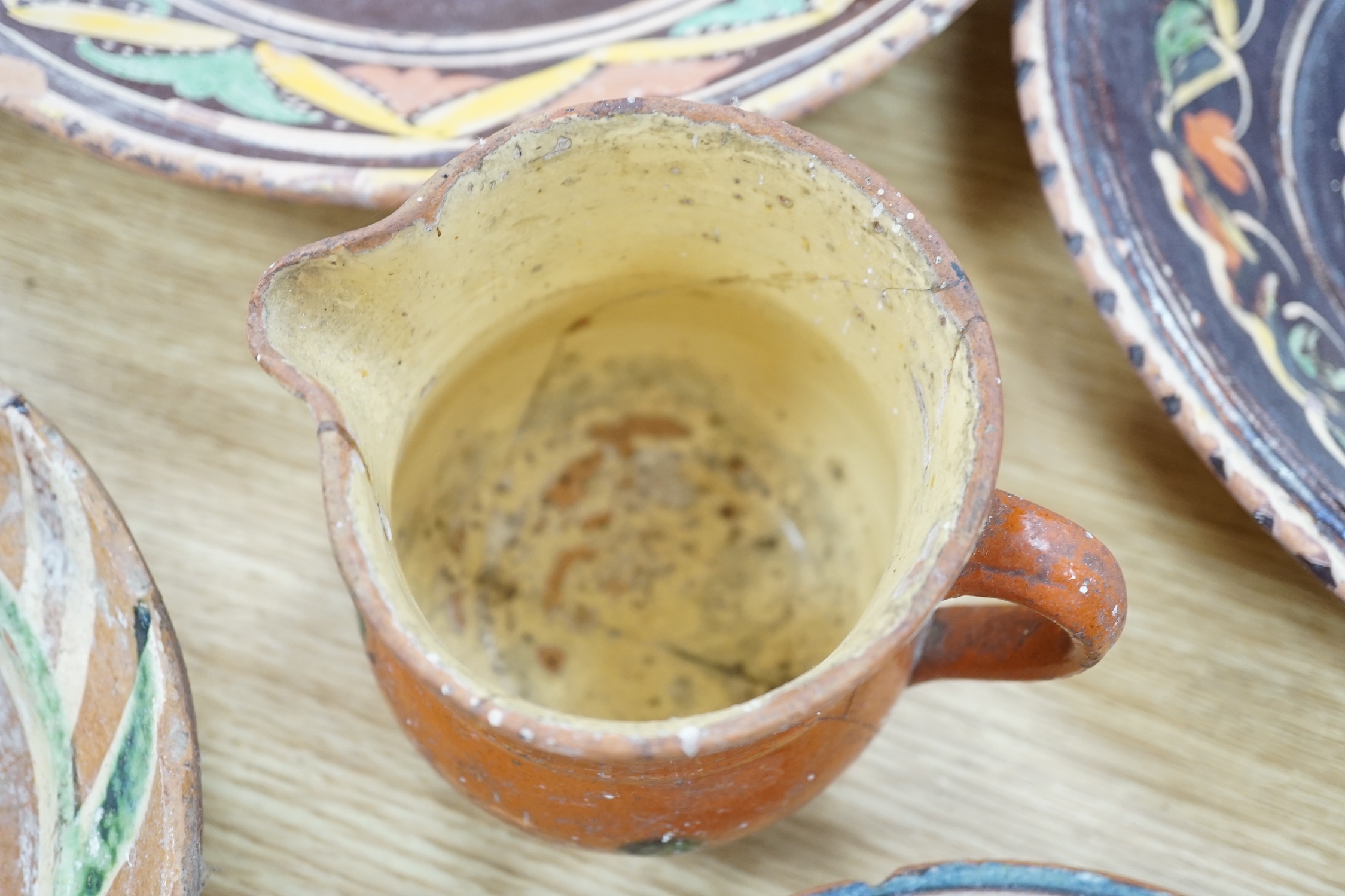 A group of Mediterranean slipware dishes, bowls and jugs, decorated in colours on a predominantly brown or ochre ground, the largest 33cm in diameter